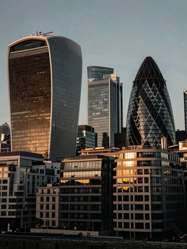 Wide architectural angle of the London financial district skyline at golden hour, deep charcoal shadows, warm light reflecting off glass facades, 35mm.