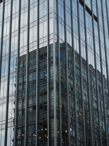 Sleek modern high-rise glass facade reflecting cool daylight, sharp architectural shadows, 35mm photography