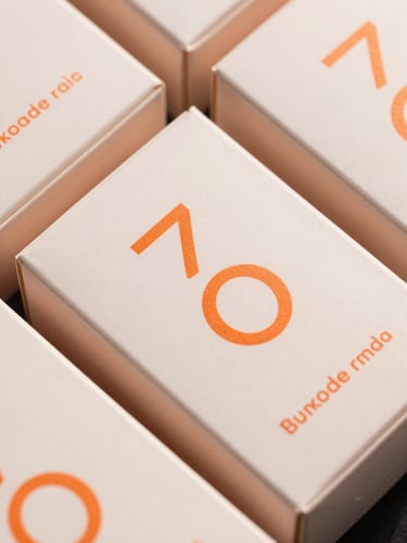 Macro top-down shot of premium matte-finish cosmetic boxes with sharp orange typography, soft studio lighting.