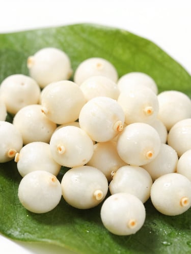 Macro shot of freshly popped snow-white makhana seeds resting on a clean dark green leaf, bright natural daylight, crisp detail, 50mm lens