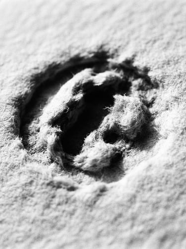 Macro close-up of heavy paper stock with deep letterpress indentation, stark shadows, high contrast black and white photography, 35mm film grain