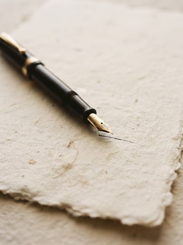Close-up of a fountain pen resting on heavy textured cotton paper, warm diffused window light, soft shadows, minimalist literary aesthetic.