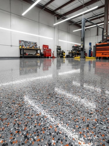 Low-angle wide shot of a pristine, newly coated garage floor reflecting overhead utility lights, sleek gray flake finish, clean edges.