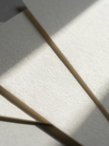 Extreme close-up of heavy embossed cotton paper stationery with sharp architectural shadows, geometric flat-lay composition, hard natural light.