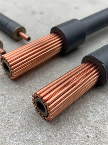 Close-up of bright, shiny stripped copper wire and thick industrial cables on a clean concrete floor, professional industrial lighting, sharp metal textures, 35mm lens
