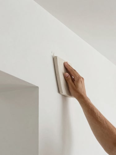 Detailed architectural close-up of a craftsman smoothing plaster on a wall, bright natural light, clean lines, professional tools