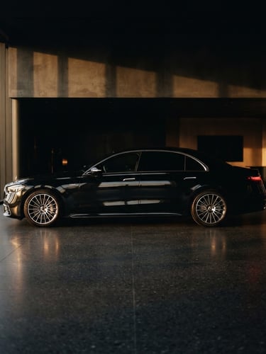 Studio-quality profile of a black Mercedes-Benz S-Class parked in a dark, minimalist showroom, dramatic side lighting reflecting off clean metallic lines, 35mm cinematic style.