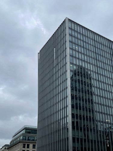 Wide panoramic architectural shot of One Coleman Street in the City of London, steel and glass facade under a cool overcast sky, sharp angles, negative space on the left