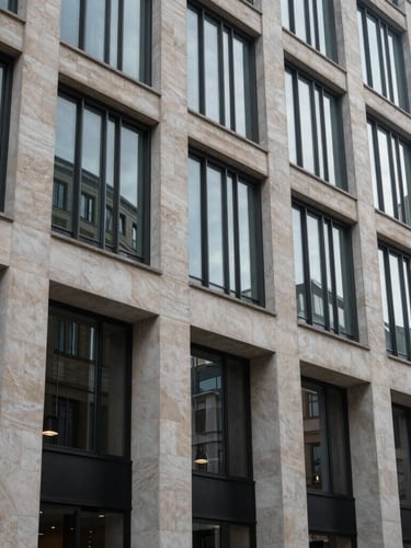 Plan plano cerrado de la fachada de piedra caliza y vidrio templado de un edificio financiero en la City de Londres, luz de día fría y difusa.