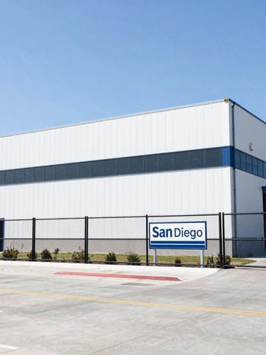 Clean architectural shot of the modern San Diego distribution facility exterior with secure fencing and clear signage under bright daylight