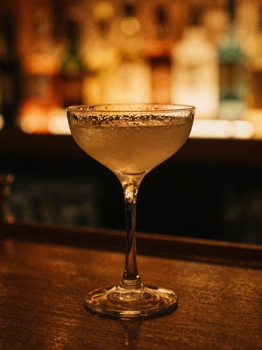 Tight macro shot of a condensation-beaded cocktail glass on a dark wood bar, warm amber lighting, golden neon glow in the background, 35mm film grain