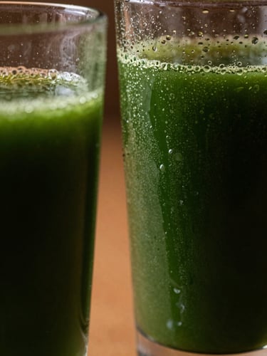 Macro close-up of condensation on elegant glassware filled with deep green cold-pressed juice, dramatic side daylight, deep shadows, rich forest green tones.