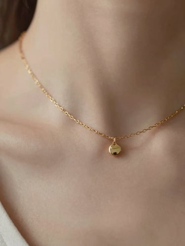 Extreme close-up of a delicate gold chain resting on a bare collarbone, soft natural daylight, warm neutral tones, shallow depth of field.