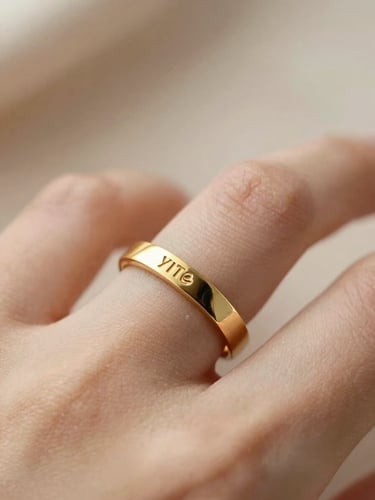 Macro shot of a custom engraved gold ring on a finger, warm neutral tones, soft natural daylight, elegant lifestyle portrait.