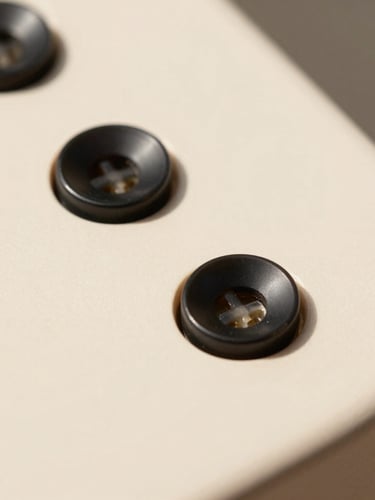 Macro close-up of physical black buttons on a warm cream matte device, hard direct sunlight with sharp shadows, minimalist product photography