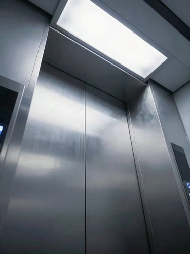 Low-angle looking up a modern illuminated elevator shaft, sharp metallic reflections, cool crisp architectural lighting, 35mm lens
