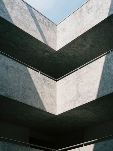 Low angle shot of a modern concrete atrium with clean geometric skylights casting sharp shadows, cool grey tones, 35mm lens