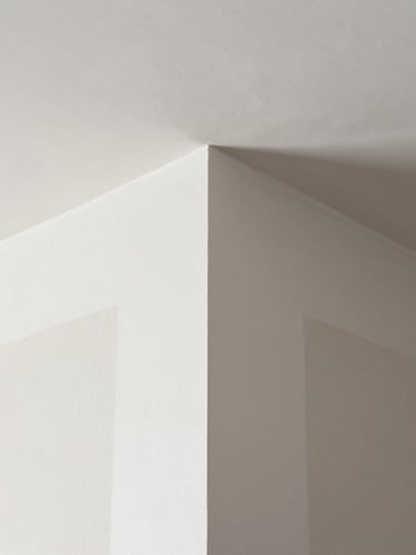 Warm natural light raking across a perfectly smooth, finished Level 5 plaster wall in a modern Seattle home, highlighting crisp corners and flawless texture.