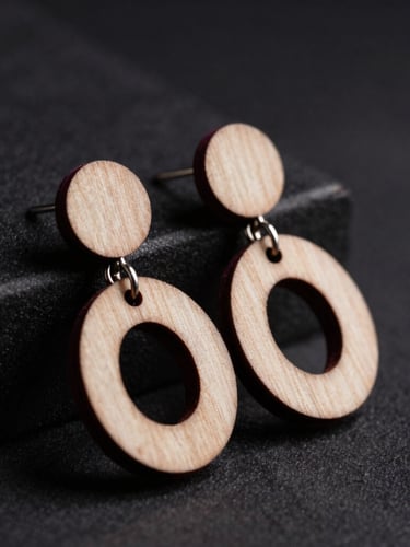 moody studio photography, dramatic low-key side-lighting, macro shot of laser-cut wood earrings catching light, rich plum accents and deep charcoal background
