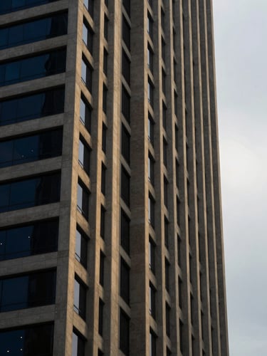 Architectural detail of a modern financial tower in Singapore, sharp geometric concrete lines against an overcast sky, low-key dramatic side-lighting, 35mm