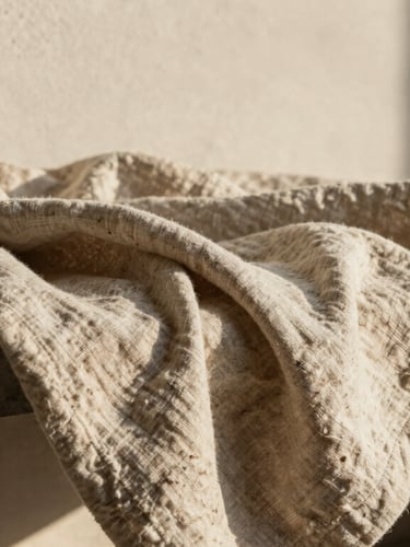 Macro shot of heavy-weight double-sided linen blanket draped over a minimalist concrete bench, raw plaster wall background, warm afternoon sun, shallow depth of field.