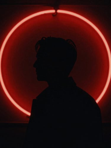 Cinematic film poster style, a dark silhouette against a vivid red neon circle, high contrast chiaroscuro, anamorphic frame, 35mm grain.