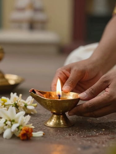 Respectful close-up of a traditional South Indian brass lamp glowing with warm natural light, elegant hands in traditional attire placing jasmine flowers nearby, soft temple background, golden hour lighting.