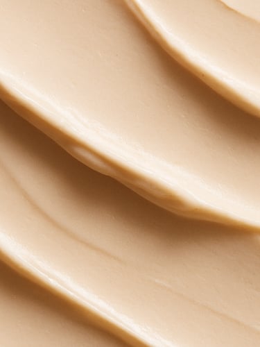 Macro beauty texture of a rich cream swatch with soft shadows, natural side-lighting, warm alabaster tones, minimalist elegant composition