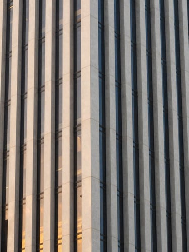 Architectural detail of modern JAFZA office tower facade in Dubai, clean vertical lines, soft golden hour window reflections, off-center composition.