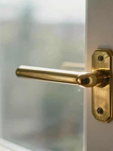 Extreme close-up of a perfectly polished brass door handle and streak-free glass panel, soft natural morning light, clean architectural lines.