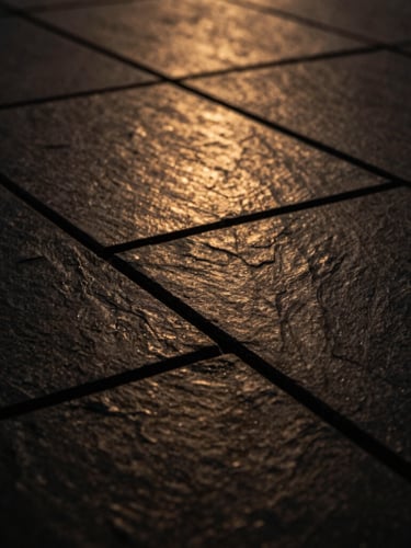 Macro close-up of structured dark slate tiles with sharp geometric lines and subtle warm gold reflections, low-key dramatic lighting, architectural photography, 35mm
