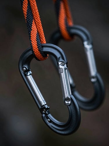 Macro photography of technical climbing ropes in black and safety orange, with highly detailed anodized aluminum carabiners and a technical descender in sharp focus, shallow depth of field, dark dramatic lighting