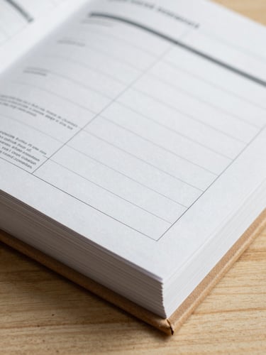 Close-up of a printed brand guidelines book, thick open-stitch binding, raw oak cover, showcasing structured grid layouts