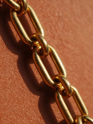 Macro close-up of heavy 21-karat gold links reflecting warm golden-hour sunlight, sharp focus, terracotta background, 35mm