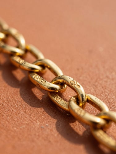 Macro close-up of a heavy 21k gold chain reflecting warm golden-hour sunlight on a terracotta surface, sharp focus on the intricate links and stamped hallmark, 35mm