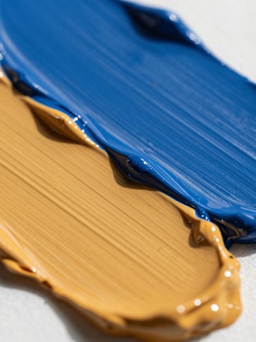 Angled macro close-up of thick, textured acrylic paint ridges on canvas, rich cobalt blue and warm ochre pigments catching natural daylight, 35mm gallery photography
