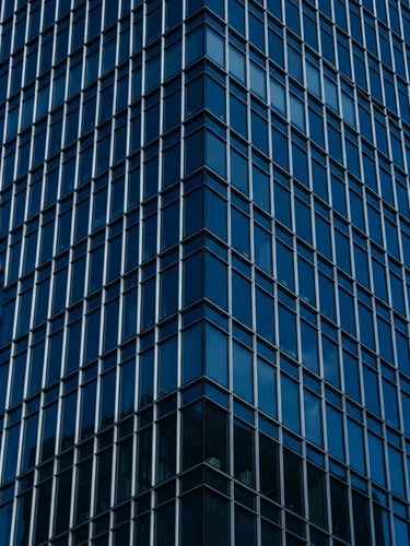 Minimalist corporate architecture, sharp steel and glass facade, deep blue tones, clean geometric lines, 35mm lens