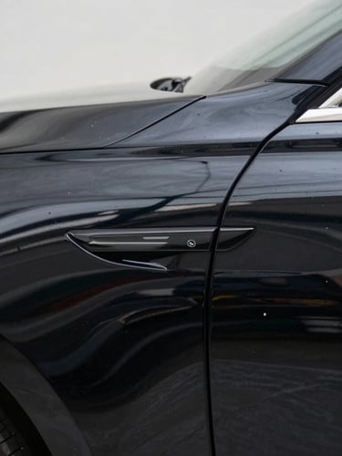 Macro shot of a freshly polished deep black car fender reflecting crisp architectural lines under soft studio light