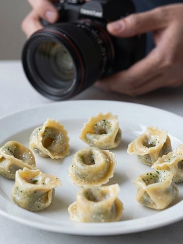 Close-up of a food photographer adjusting lighting over a plate of hand-made tortellini, soft natural side-light, Scandinavian aesthetic.