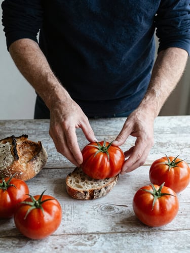 Candid shot of a creative director arranging organic tomatoes and sourdough on a rustic table, soft natural side-light, editorial food photography style