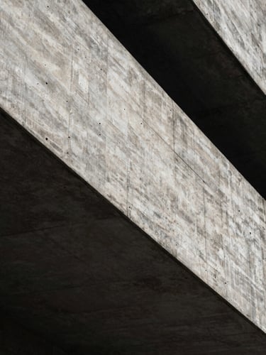 Abstract close-up of a monolithic brutalist concrete structure with deep shadows and sharp geometric lines, low-key dramatic side-lighting.
