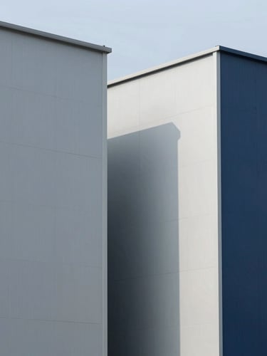 Industrial facility exterior with sharp architectural lines, bright daylight, cool gray and navy tones, sharp focus, 35mm