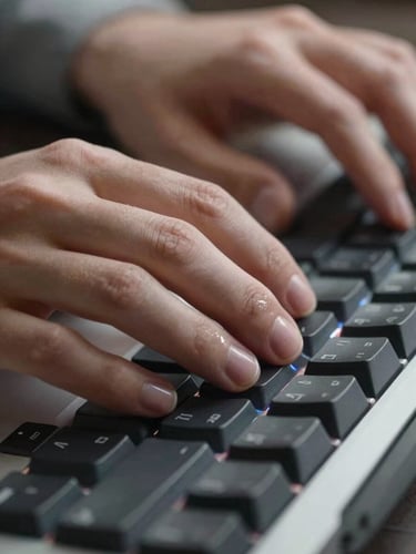 Close-up of hands resting on a mechanical keyboard, screen glow reflecting off fingertips, a tool interface visible in soft focus behind — clean studio key light, cropped tight to show the action