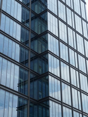 Crisp corporate photography, bright cool daylight, clean glass reflections, modern Bengaluru financial district building facade with structured geometric lines, 35mm