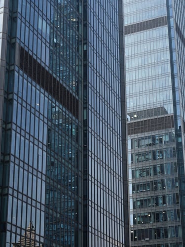 Sharp architectural crop of modern glass financial towers in Bengaluru, crisp cool daylight, clean glass reflections, deep navy and slate tones, 35mm.