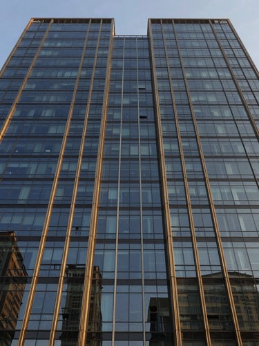 Symmetrical wide-angle architectural photograph of a modern glass office tower facade in Gurgaon, crisp golden-hour sunlight reflecting off clean glass panels, deep navy shadows, premium corporate aesthetic