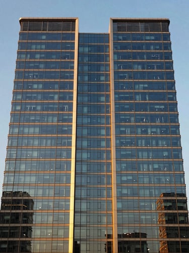 Symmetrical modern office tower facade in Gurgaon, clean glass reflections, sharp golden-hour sunlight, premium architectural photography