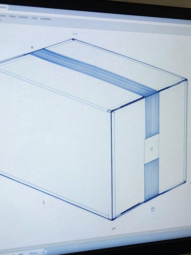 Technical CAD drawing of a cardboard box structural design on a monitor screen, cool daylight, blue and white tones, sharp focus on blueprint lines