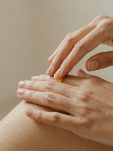 Close-up portrait shot of hands gently applying botanical oils on clean skin, soft diffused warm daylight, natural textures, shallow depth of field.