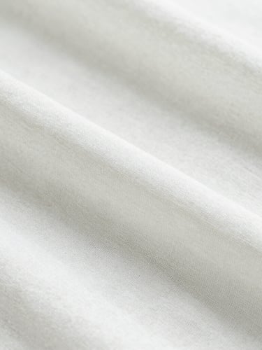Minimalist macro photography of soft white linen fabric texture under gentle morning sunlight, clean and fresh atmosphere